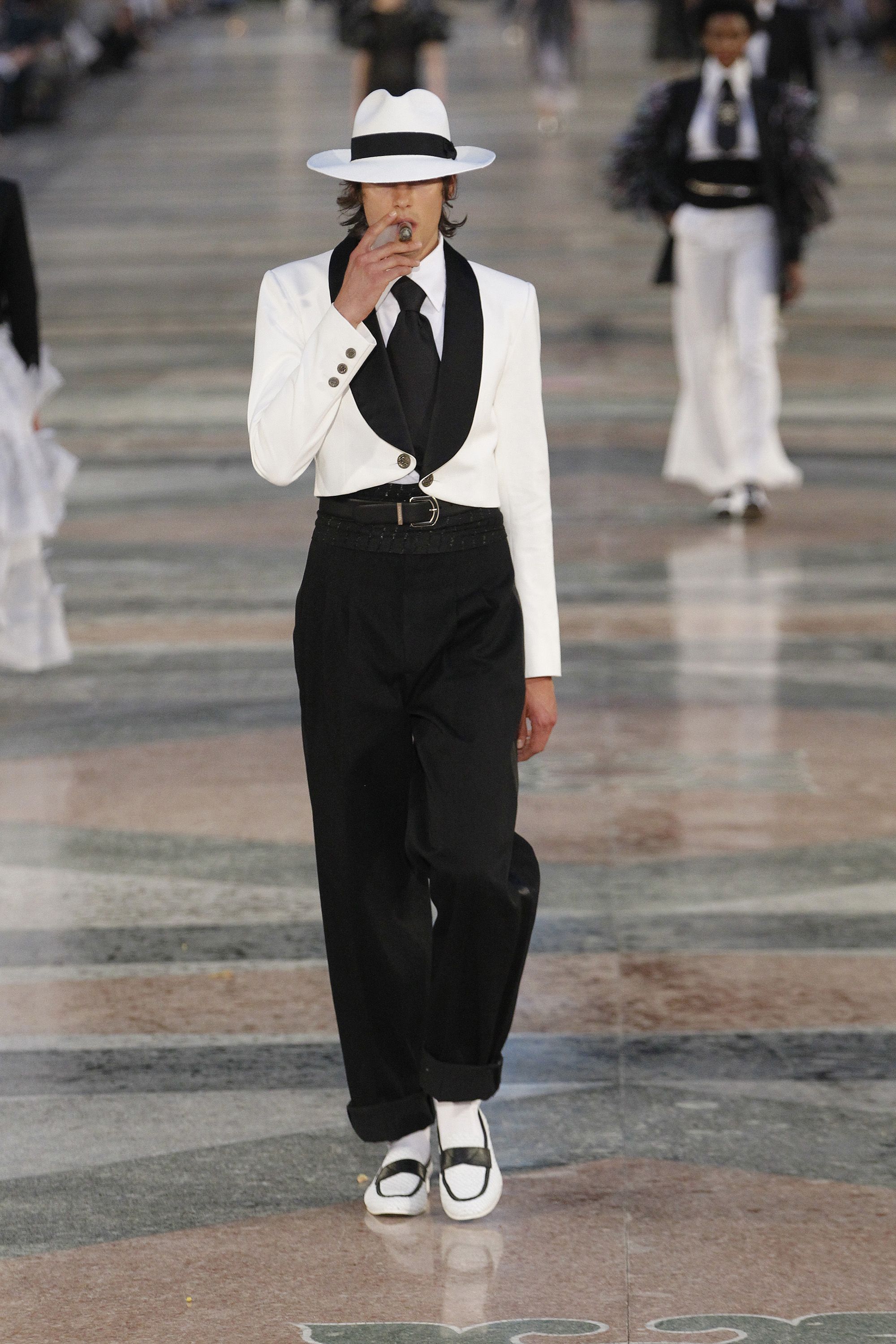 Image may contain Clothing Formal Wear Suit Pants Person Accessories Tie Adult Hat and Coat