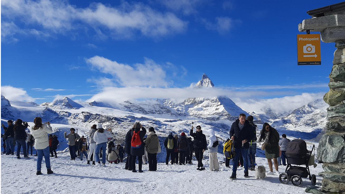 Figure 4 — Taking advantage of the photopoint in Zermatt, November 2022. Copyright 2022 by A. Boscoboinik.  phers’ arms and heads in the shot (Mourtazina, 2019).  Matterhorn is encouraged to the point that the tourist office has established a touristic route, indicating the best viewpoints (photopoints) from which to photograph the famous mountain (Fig. 4). There are additionally many indi- vidual tactics for capturing the “best picture” of the Matterhorn, including one particularly perilous strategy to avoid capturing other tourist photogra- phers’ arms and heads in the shot (Mourtazina, 2019). 