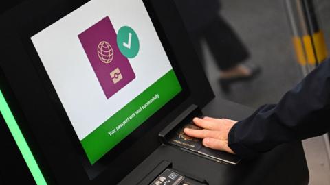Close up of a person's hand wearing a wedding ring holding down a British passport on a scanner during a demonstration of the new system in September at the Eurostar terminal in Folkestone.